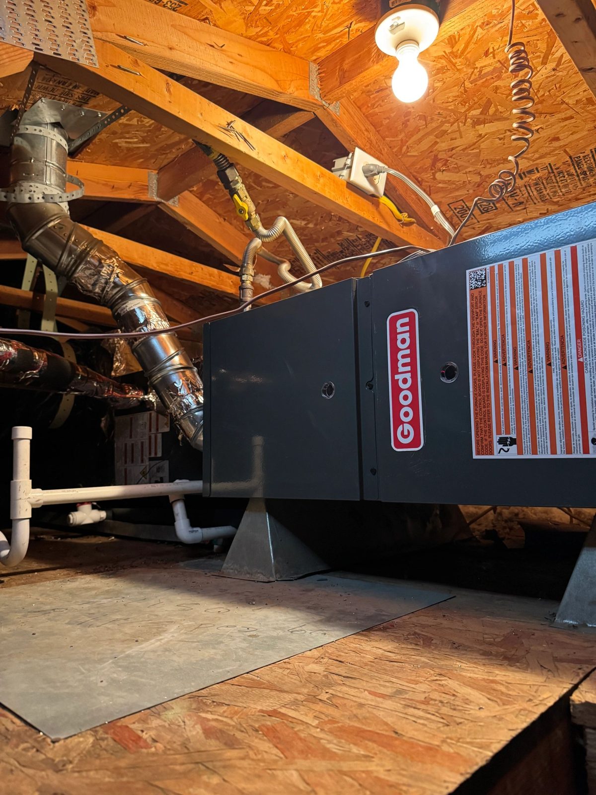 Goodman HVAC unit in attic with ducts and piping