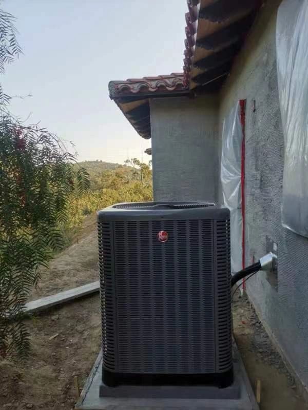 Rheem 5-ton heat pump outdoor unit installed beside a new home