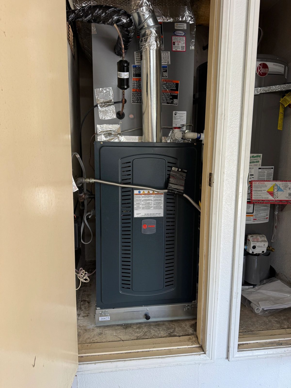 Trane HVAC furnace unit in closet with ducts and water heater