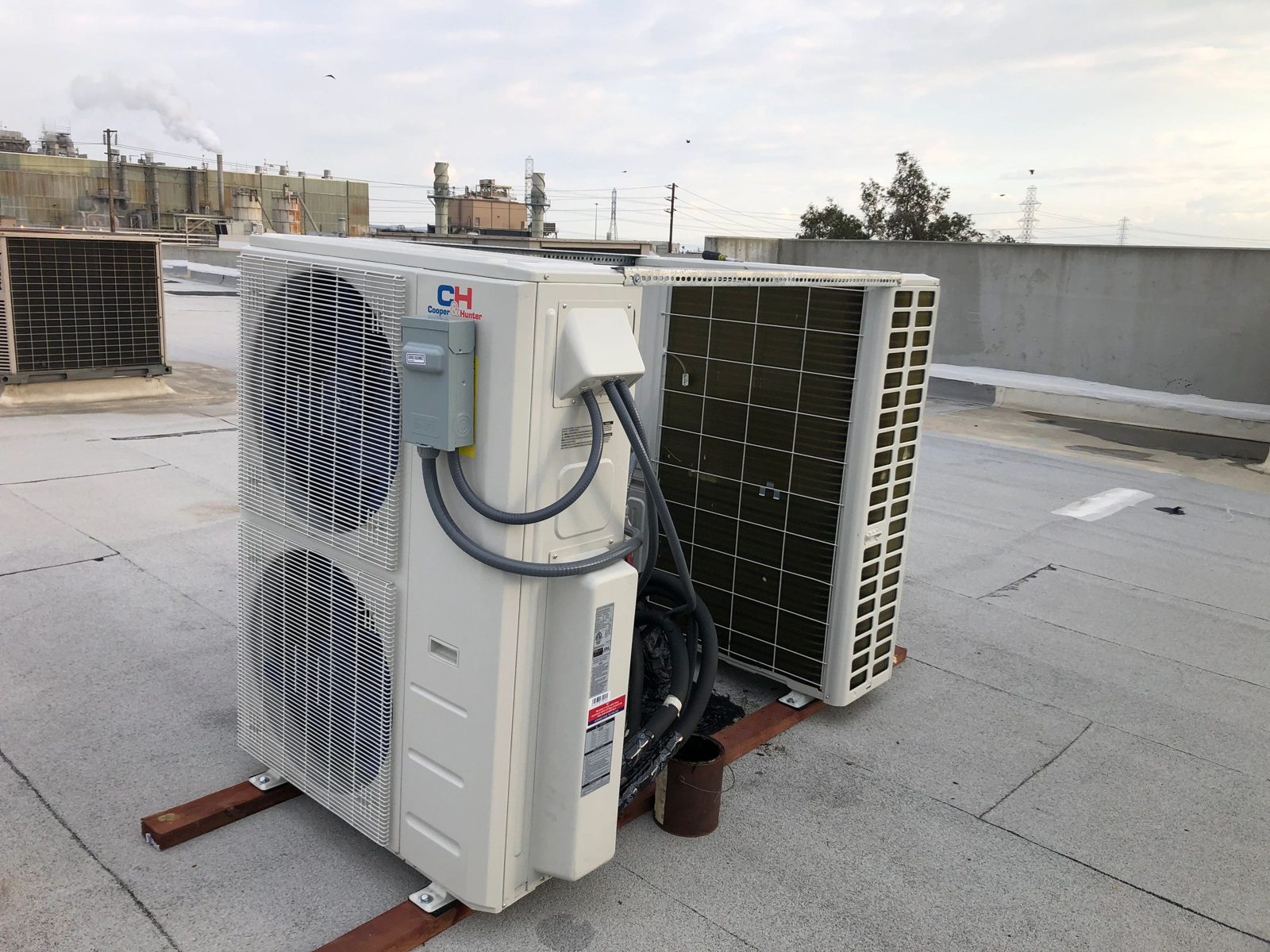 Technician installing ductless heat pump unit in warehouse