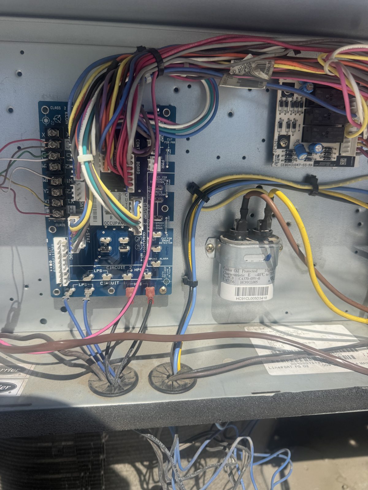 HVAC control board with colorful wires and capacitor inside unit during Chino repair
