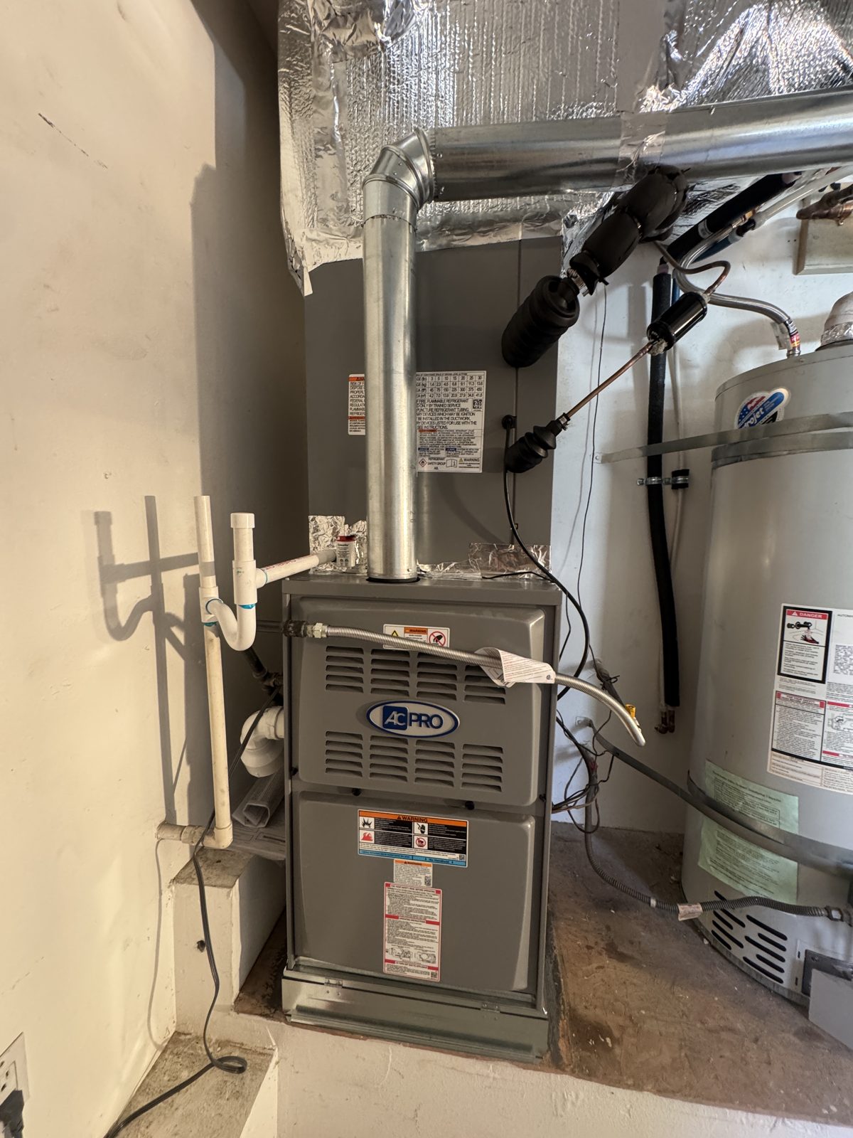 HVAC furnace with vent pipe next to water heater and outdoor AC unit on pad in Chino Hills
