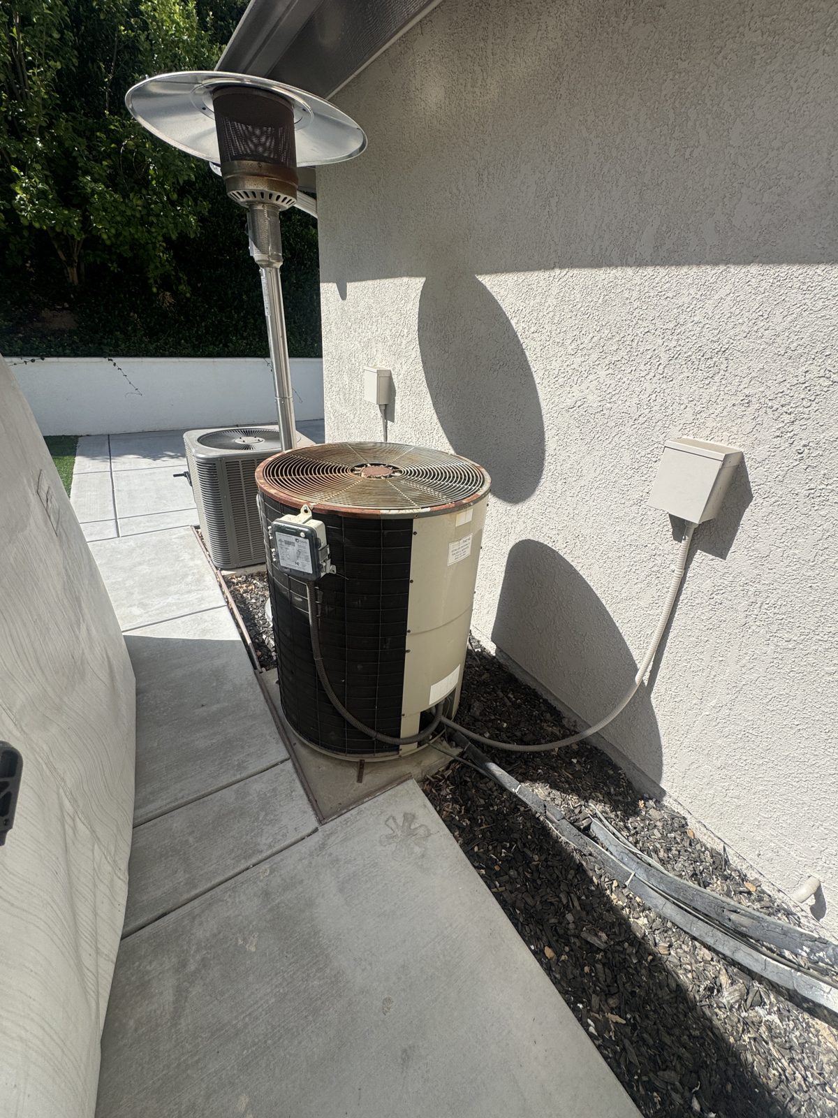 Outdoor HVAC condensers and heater by stucco wall in Chino Hills