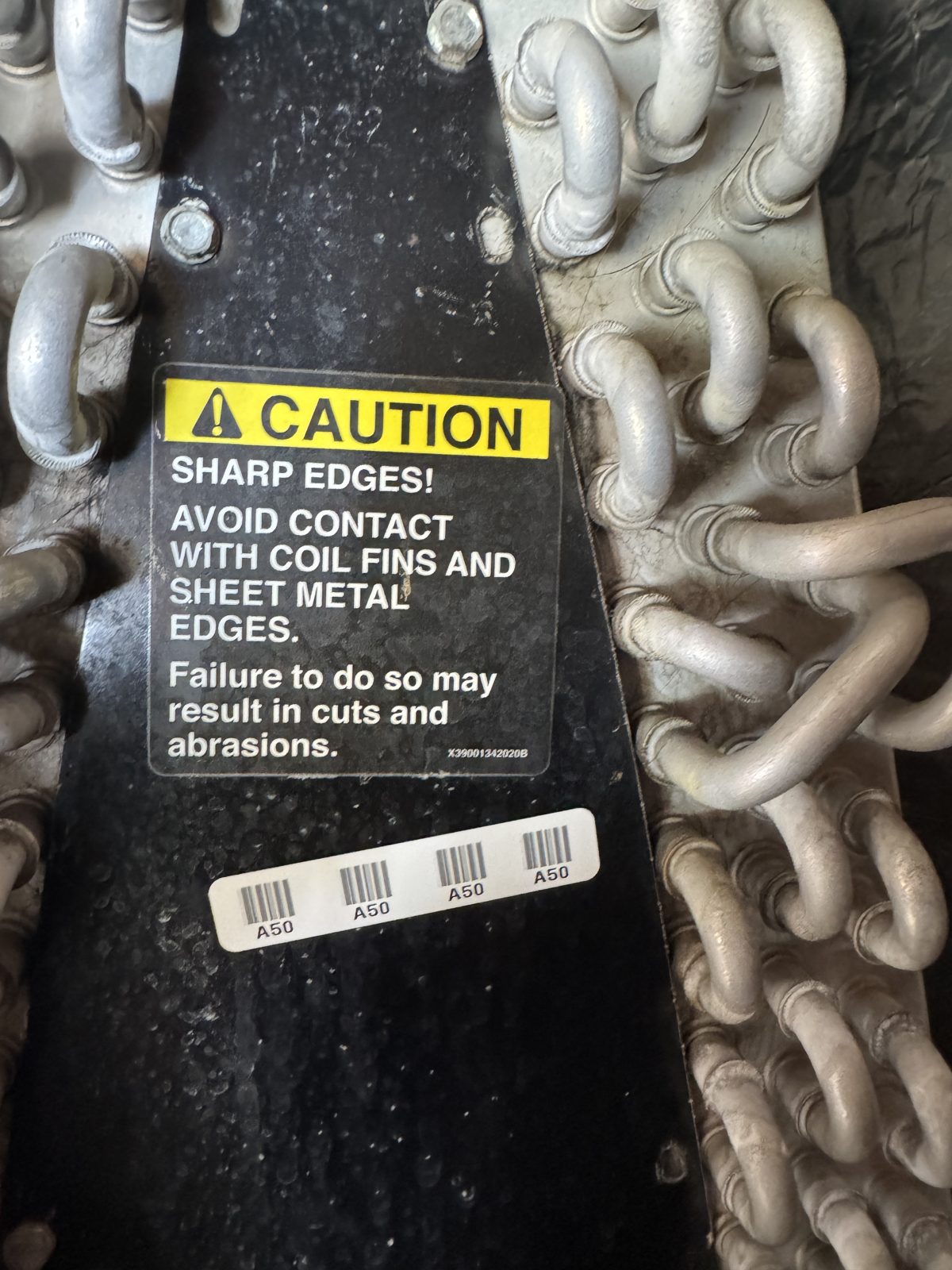 Caution sticker on finned coils and pipes with HVAC coils, pipes, gauge and tools on old unit during Chino Hills repair