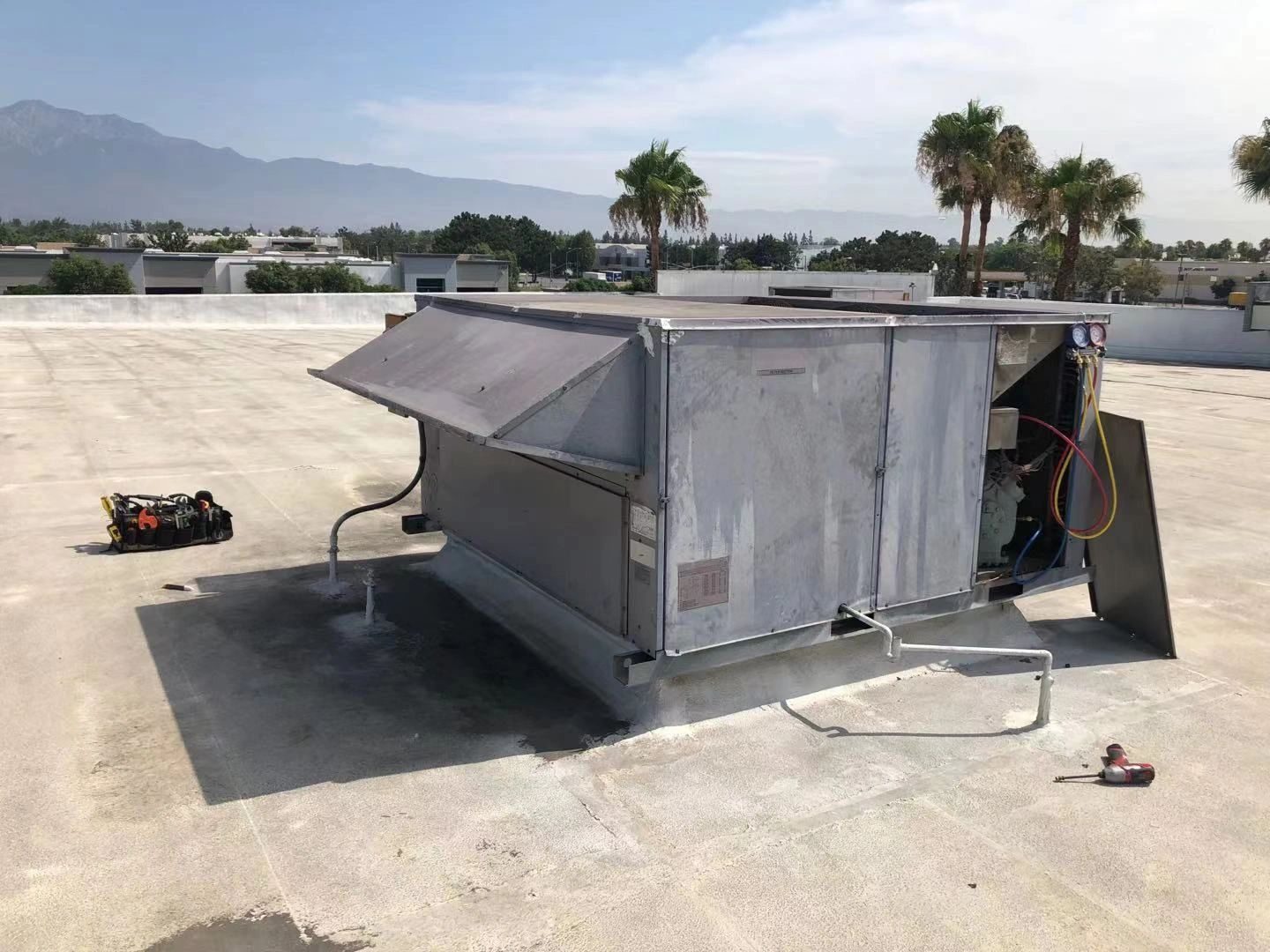 Technician performing HVAC preventive maintenance on office building rooftop unit