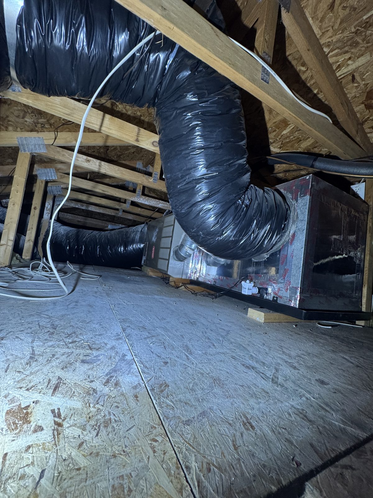 Attic view showing black HVAC ducts connected to metal unit during Rancho Cucamonga repair