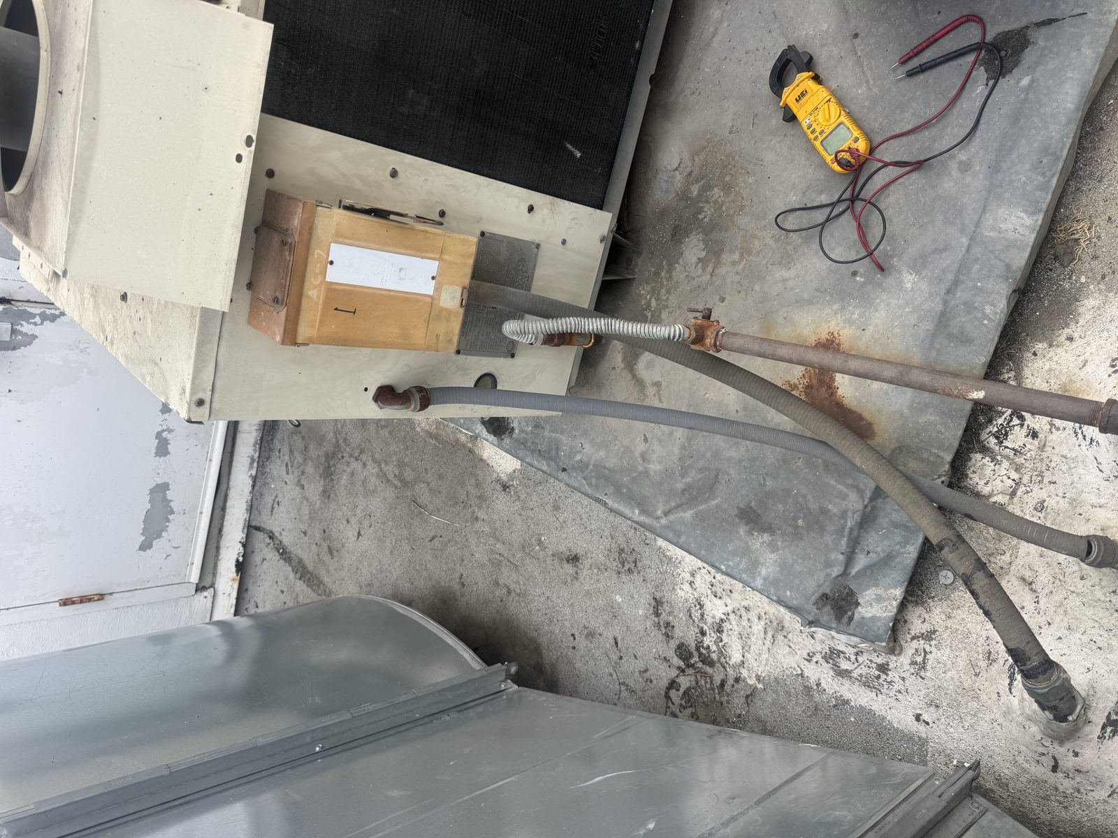 HVAC unit with pipes and multimeter on rooftop during Riverside diagnostic visit